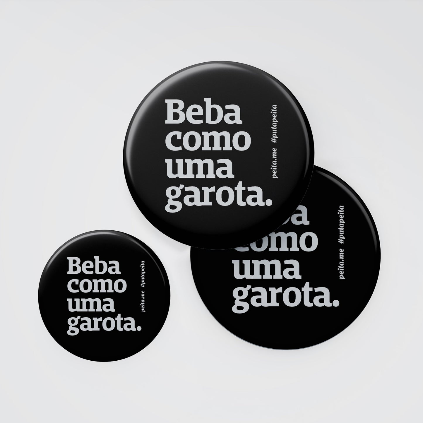 Mockup de 3 abridores de garrafa arredondados preto escrito Beba como uma garota em branco. Um dos abridores sobressai o outro e o terceiro esta mais afastado. Fundo branco.